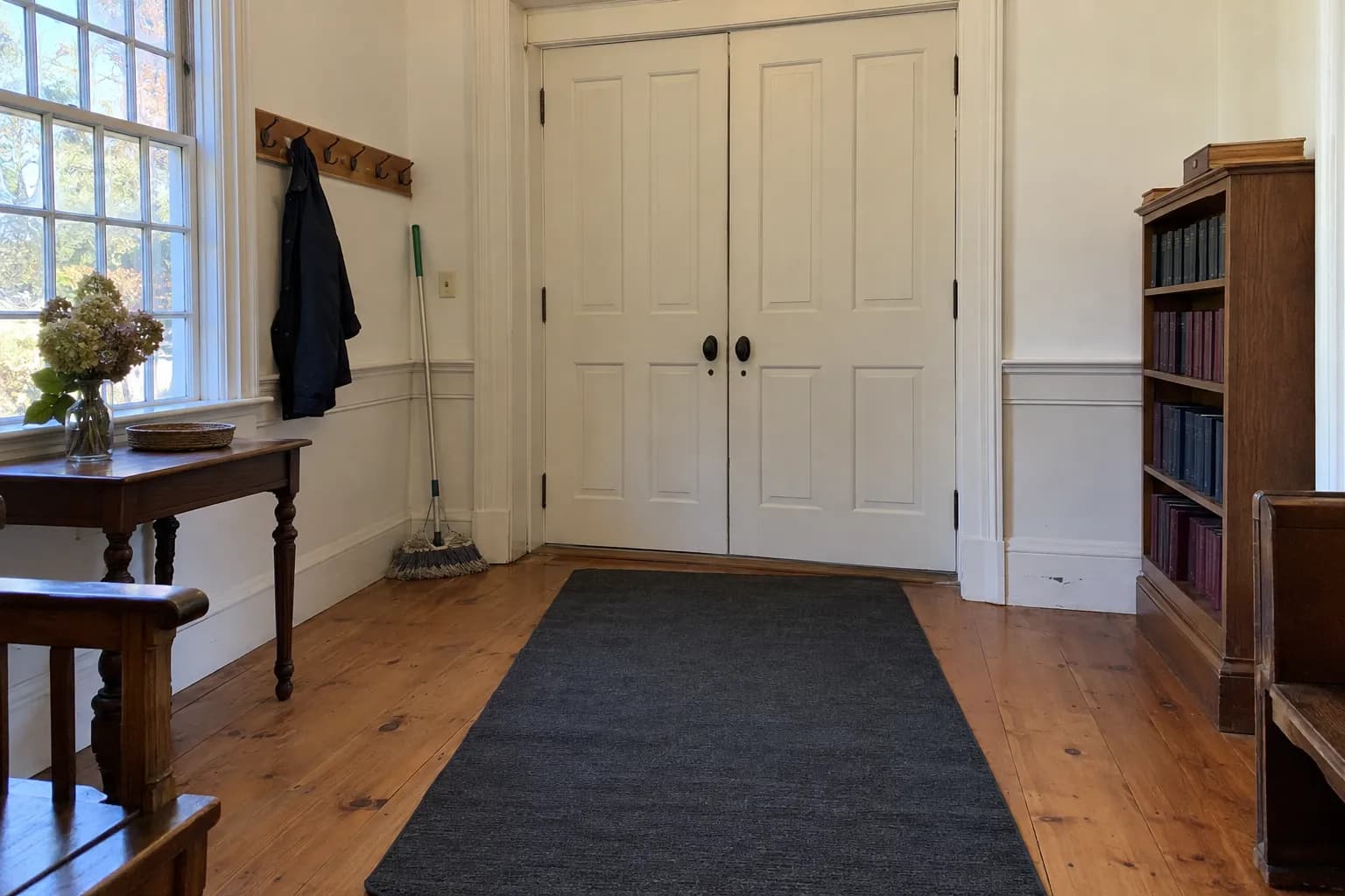 The swept wooden entry hall of a historic church with a broom in the corner