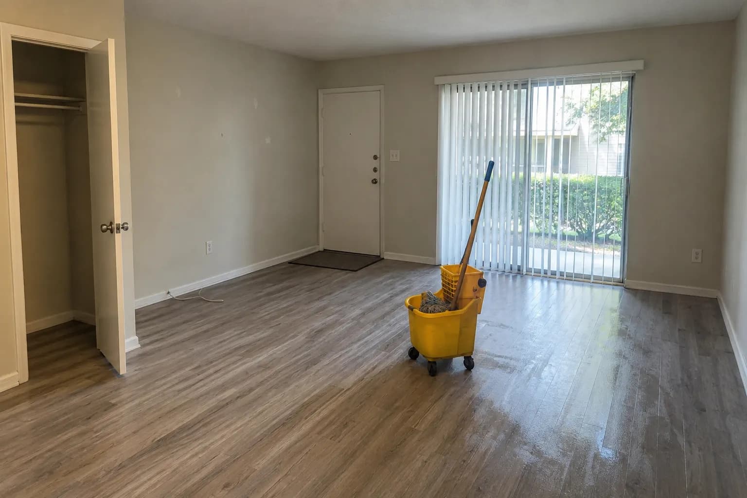 A vacated rental apartment living room with a mop bucket on the freshly mopped floor