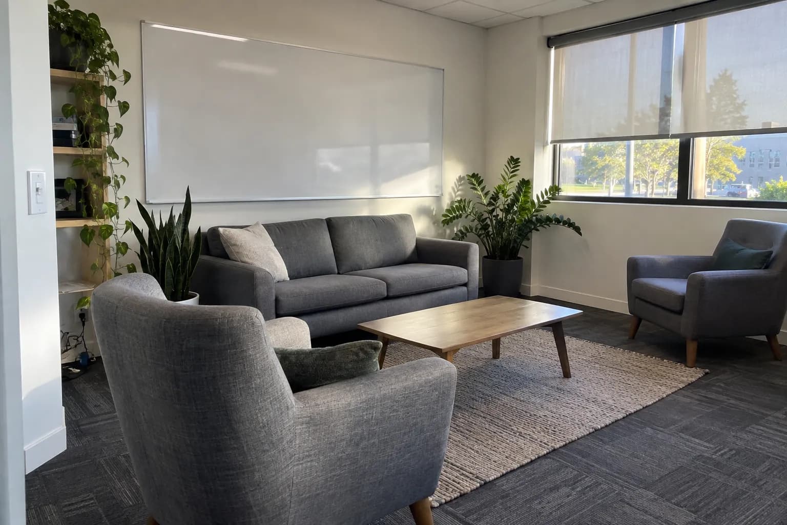 An office lounge area with a wiped coffee table and a blank whiteboard in morning light